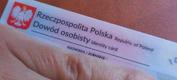 dowód osobisty z zakrytymi dłonią danymi. Zdjęcie poglądowe.